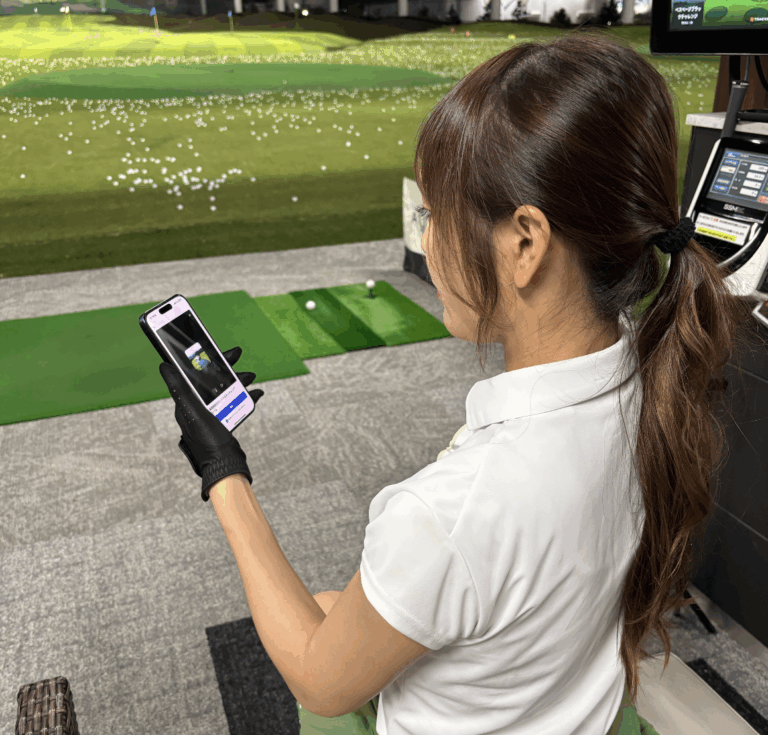 練習場でスマホを見ながらスイングを確かめる様子